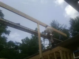 Carpenter setting a ridge beam over a new addition frame — Ice Dam Removal by Roofing Brothers in Elmont