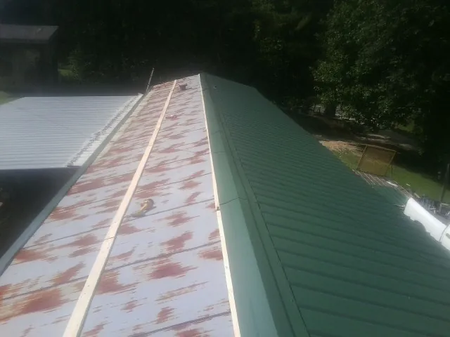 Old rusted panels beside newly installed green metal roofing — Wind Damage Roof Repair by Roofing Brothers in Elmont