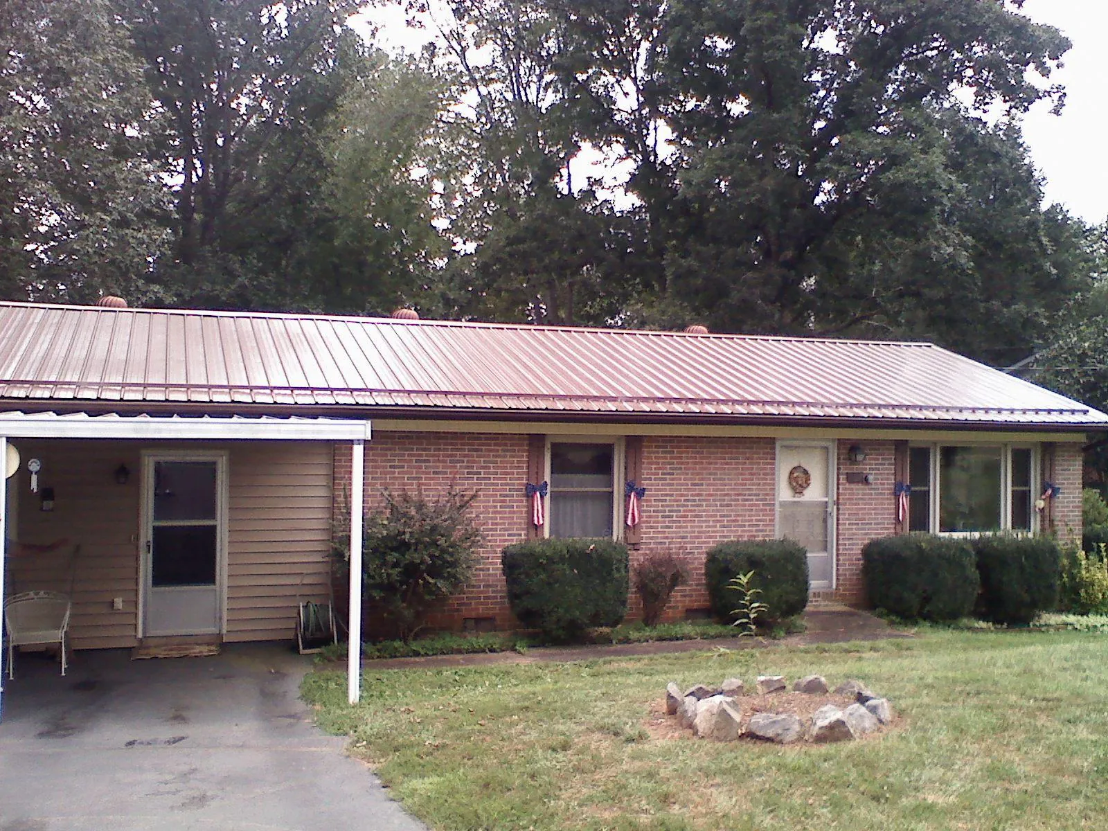 Bronze metal roof and carport on a brick ranch home — Roof Repair work by our crew in Elmont