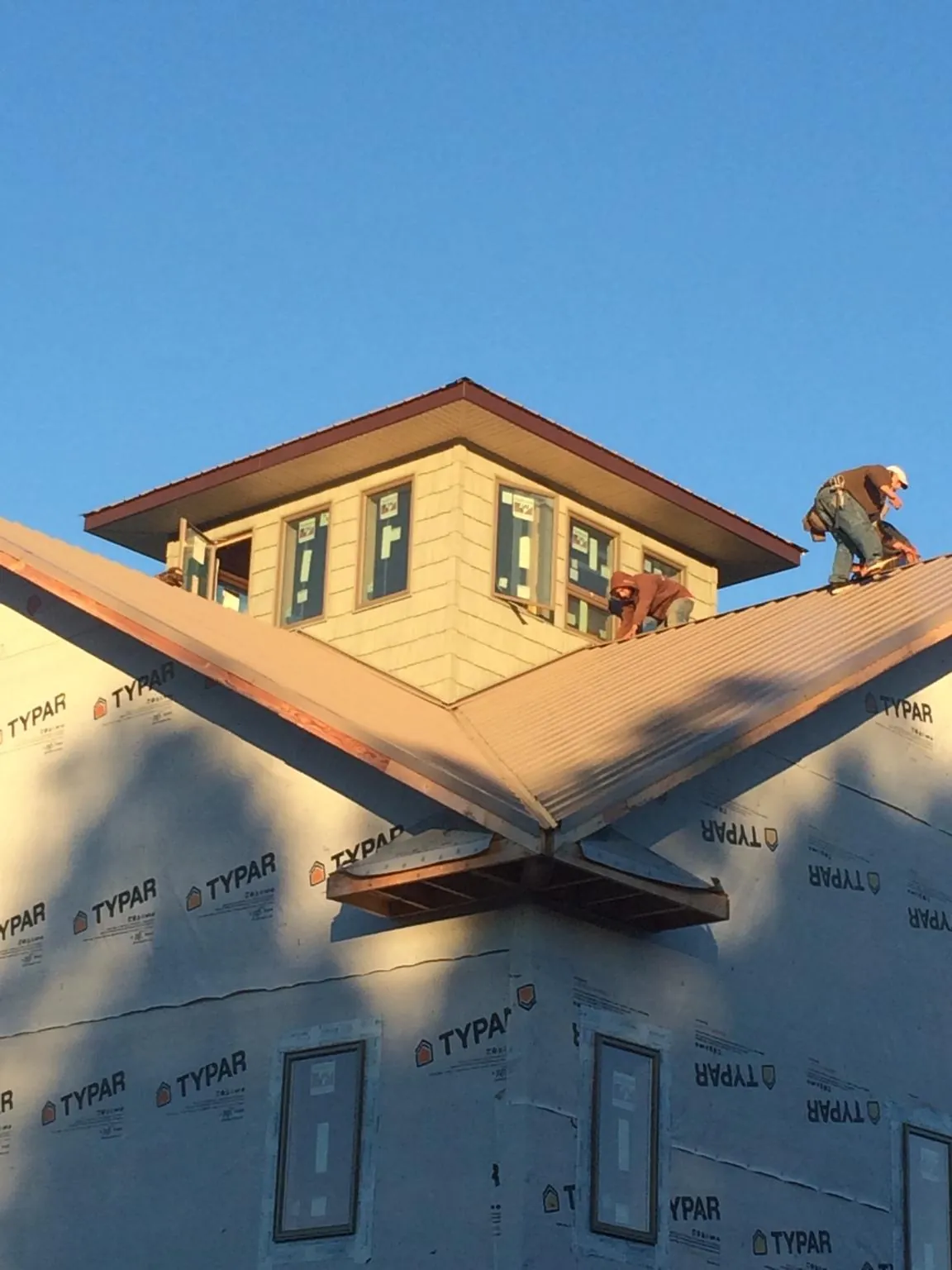 Roofers working around a rooftop cupola on a new metal roof at sunset — Roof Waterproofing in Elmont by Roofing Brothers